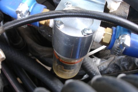 1995 Ford Taurus - A close-up view of an engine component with blue hoses and a visible warning label.