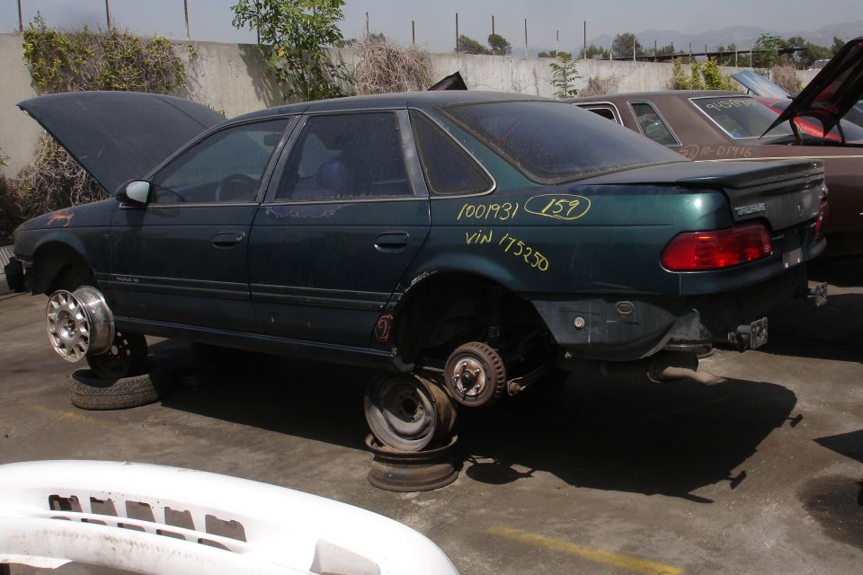 1993 Ford Taurus side view, dark green, missing wheels and hood