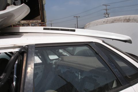 1993 Ford Taurus - A white car roof spoiler is mounted above the rear window of a vehicle.