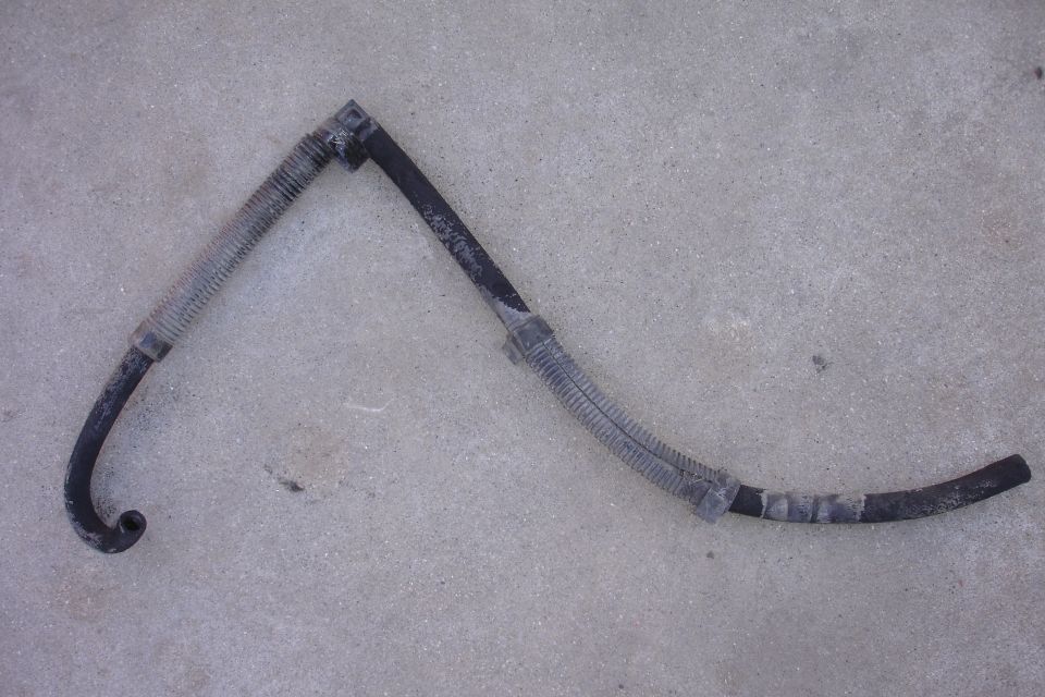 Automotive hose with ribbed sections and black rubber tubing, lying on a concrete surface