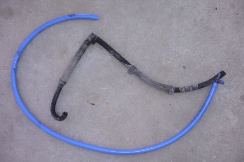 1995 Ford Taurus - Two automotive hoses, one blue and one black with corrugated sections, are shown on a concrete surface.