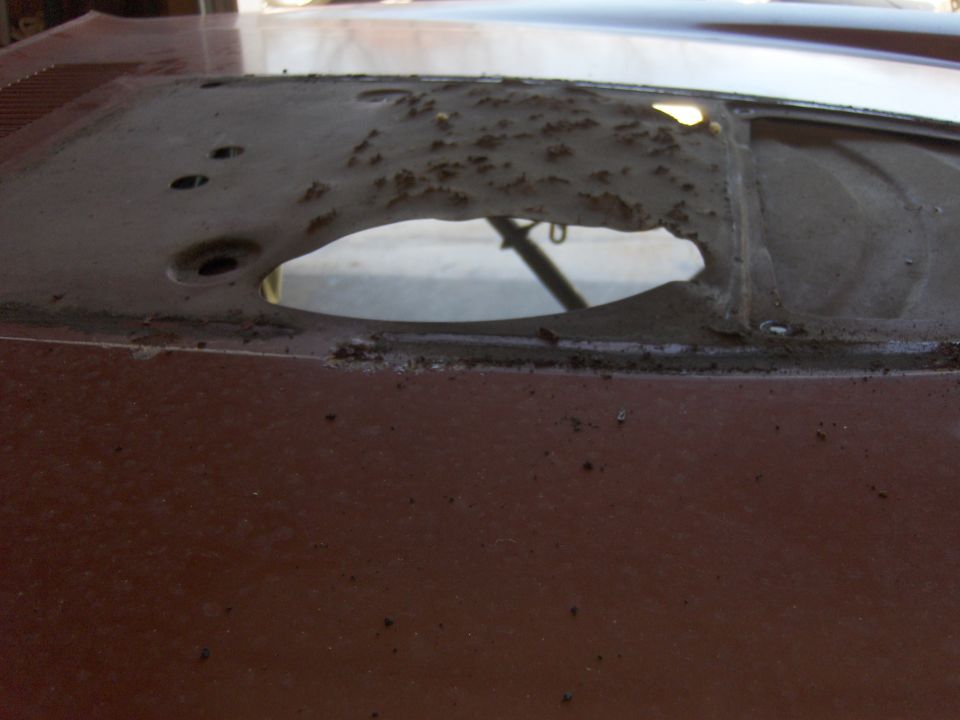 Rusted rear window frame of a brown vehicle