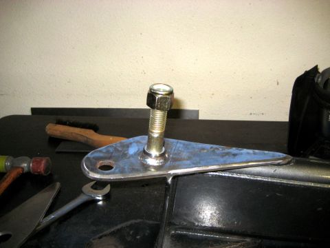 1996 Ford Bronco - A close-up of a metal suspension component with a bolt and nut, alongside various tools.