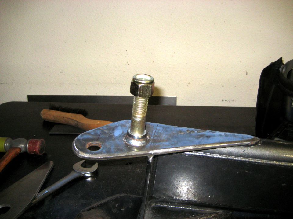Metal suspension part with a bolt and nut, on a workbench with tools