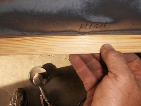 1980 Chevrolet Camaro - An inspection mirror is visible on the floor near a hand holding a piece of wood trim. Text above reads 'HIGH'.