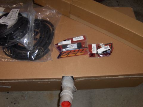 1980 Chevrolet Camaro - Various car parts, including weather stripping and emblems, are laid out on a cardboard box.
