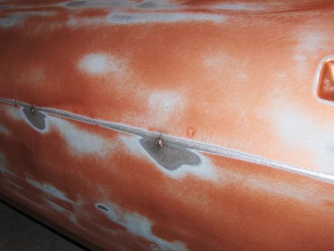 1980 Chevrolet Camaro - Detail of a car door undergoing bodywork, revealing primer and bare metal beneath the paint.