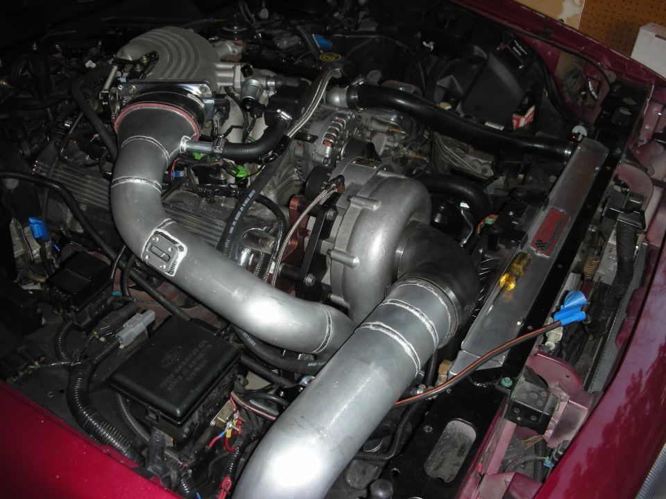 Engine bay with custom turbocharger and intercooler piping, maroon exterior visible