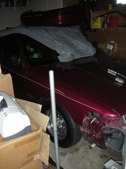 1992 Ford Crown Victoria - A maroon sedan is parked in a garage, partially covered, with its front bumper removed.