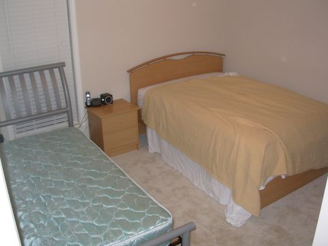 2004 Land Rover Land Rover - A bedroom scene shows two beds, a nightstand with electronics, and a window with blinds.