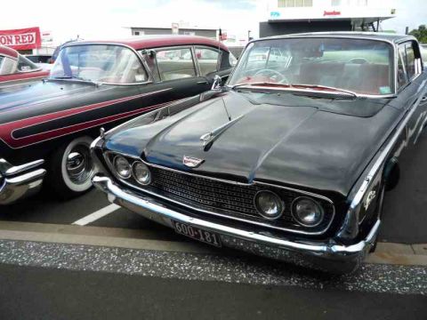 1969 Lincoln Continental - A black 1960 Ford Starliner is parked next to a red and black two-tone classic car.
