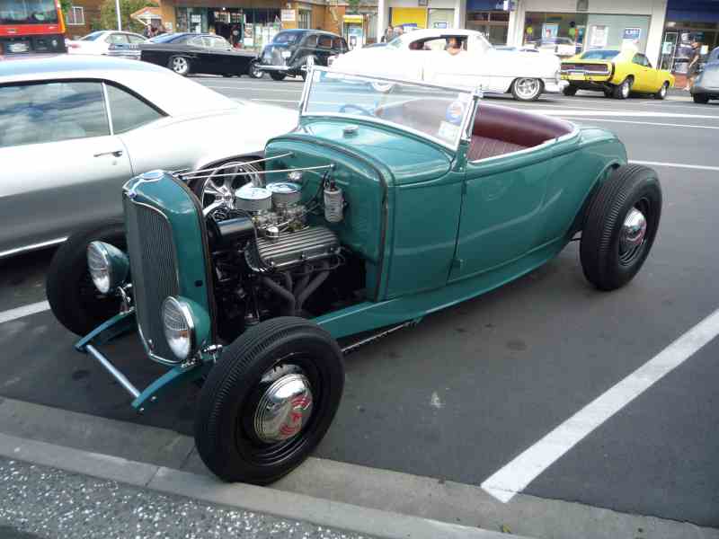 Teal hot rod roadster with exposed engine and red interior