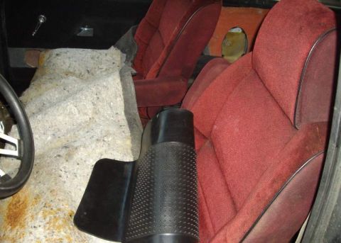 1979 Ford Bronco - Interior view of a vehicle with red seats and exposed insulation, possibly undergoing restoration.