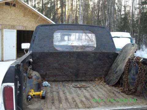 1978 Ford Bronco - The interior of a truck bed shows a plywood lining, a yellow drill, and heavy chains.