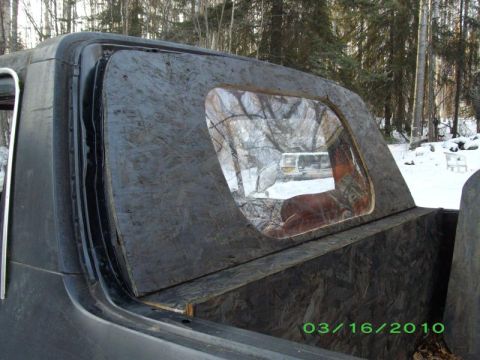 1978 Ford Bronco - Custom rear window paneling on a vehicle, with a reflection of another vehicle visible in the glass.