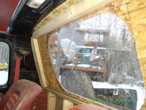 1978 Ford Bronco - Unfinished interior paneling around a window in a vehicle, with a snowy outdoor scene visible through the opening.