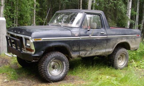 1978 Ford Bronco - A black 1978 Ford Bronco with a bull bar and off-road tires sits in a wooded area.