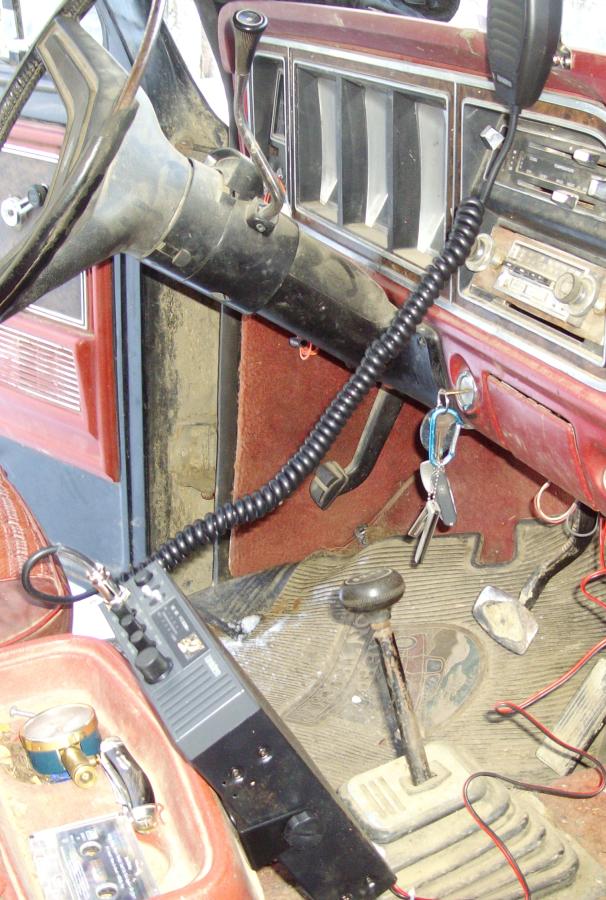 CB radio mounted under the red dash of an older Ford truck, coiled mic cord and floor shifter
