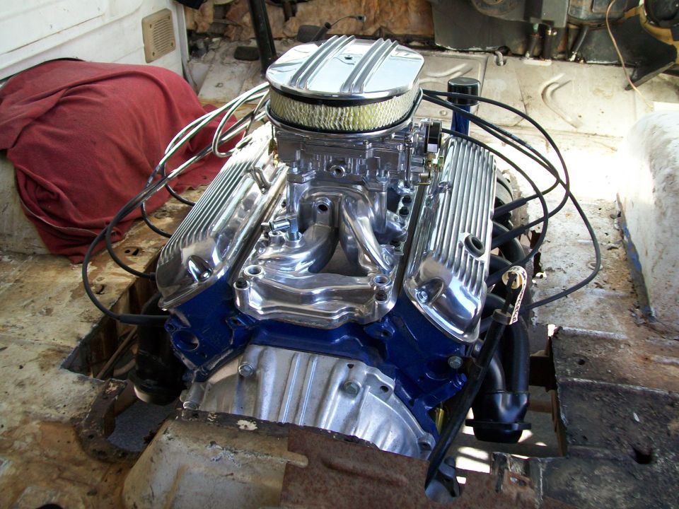 Blue Ford V8 with polished finned valve covers and chrome air cleaner in a stripped van engine bay