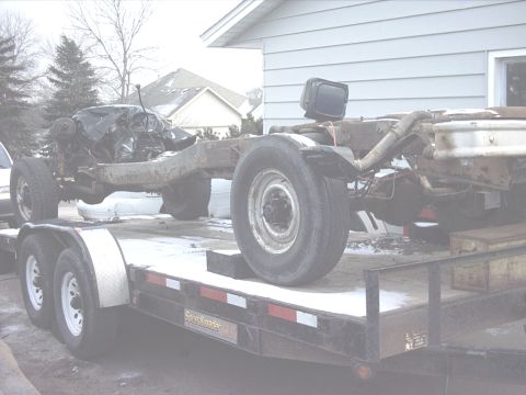 1954 Ford F-100 - Truck chassis with engine and wheels loaded onto a trailer for transport.