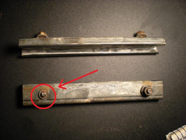 Two metal tailgate brackets, one with a red circle around a bolt