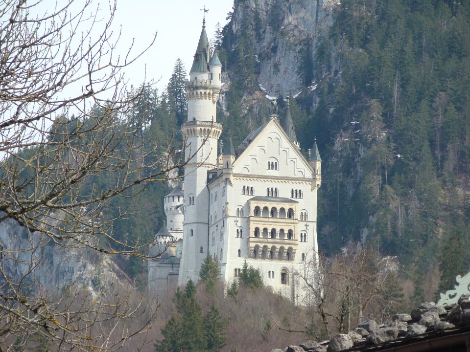 Neuschwanstein Castle in Bavaria, Germany, with forested mountains behind it