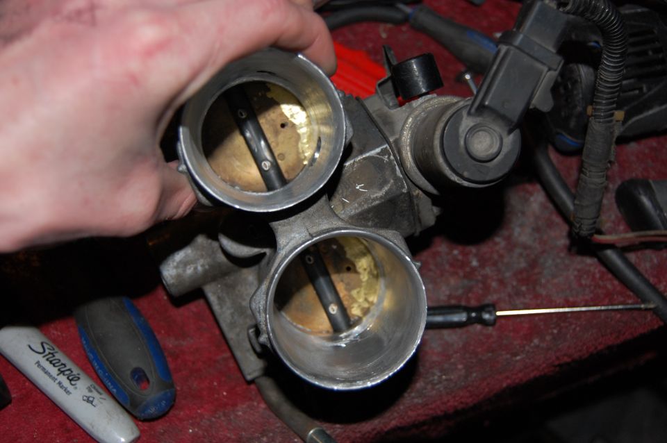 Dual throttle body with visible butterfly valves and a Sharpie marker nearby