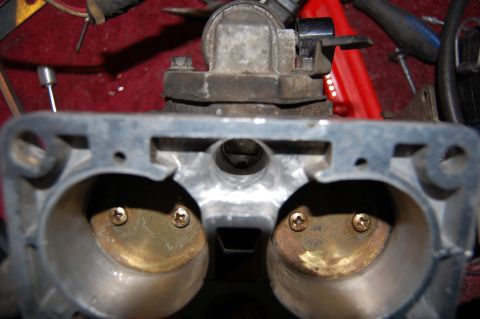 1994 Ford Bronco - Looking straight down the throat of a removed twin-bore throttle body sitting on a red shop cloth, with both brass butterfly plates closed…