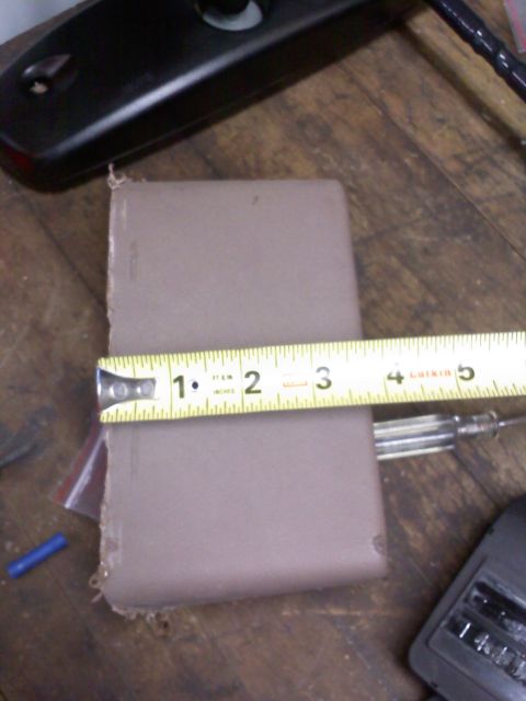 1992 Ford Bronco - A measuring tape is used to measure a brown object on a wooden surface.