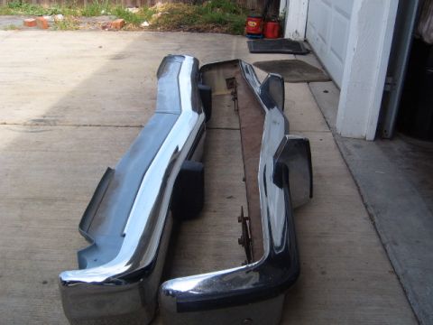 1973 Ford Ranchero - Two chrome bumpers are laid out on a driveway, possibly for restoration or sale.
