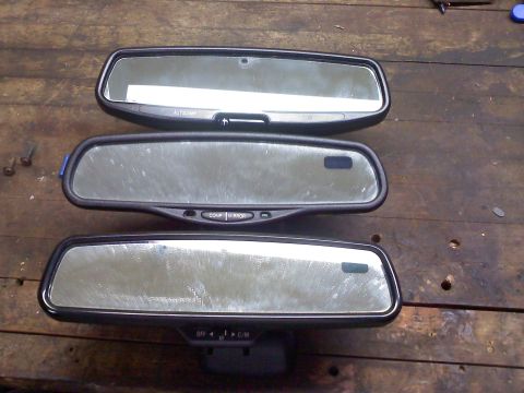 1992 Ford Bronco - Three automotive rearview mirrors, each with different control buttons, are laid out on a wooden table.