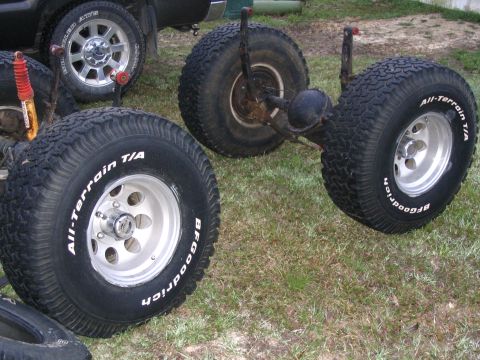 1995 Ford Bronco - Trailer axle with BFGoodrich All-Terrain T/A tires and aluminum wheels, sitting on grass.