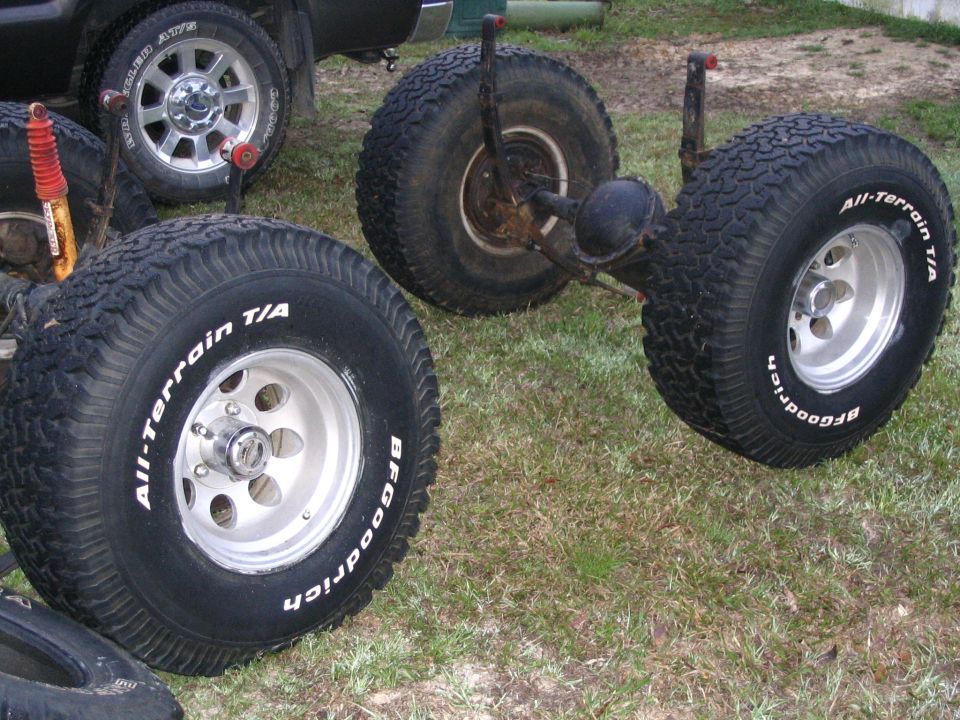 BFGoodrich All-Terrain T/A tires on polished wheels beside a bare solid axle in a yard