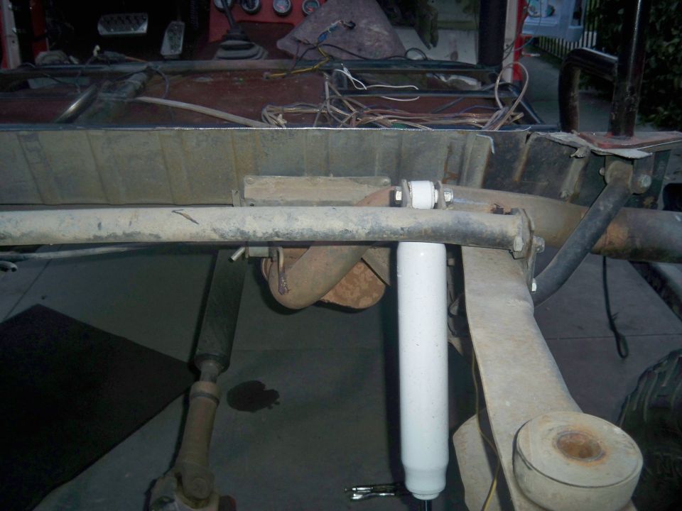 Vehicle frame with exhaust pipe and white shock absorber, viewed from below