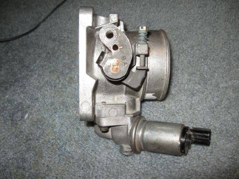 1994 Ford Bronco - A throttle body assembly, likely from an older vehicle, is shown against a carpeted background.