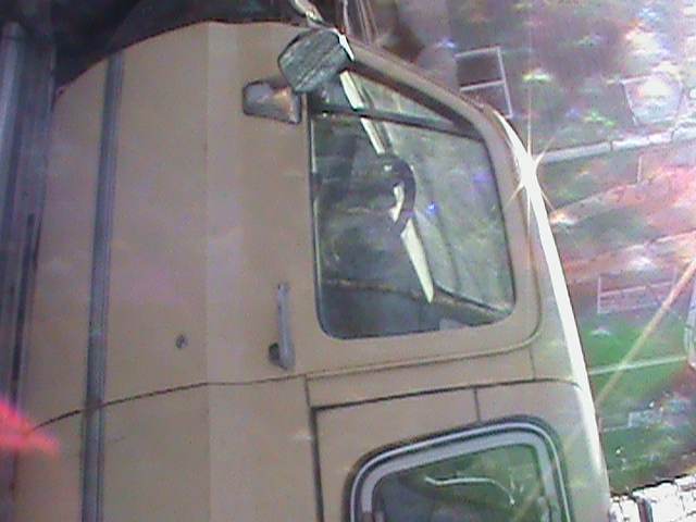 Close-up of a tan truck's cab, showing the side mirror and part of the windshield