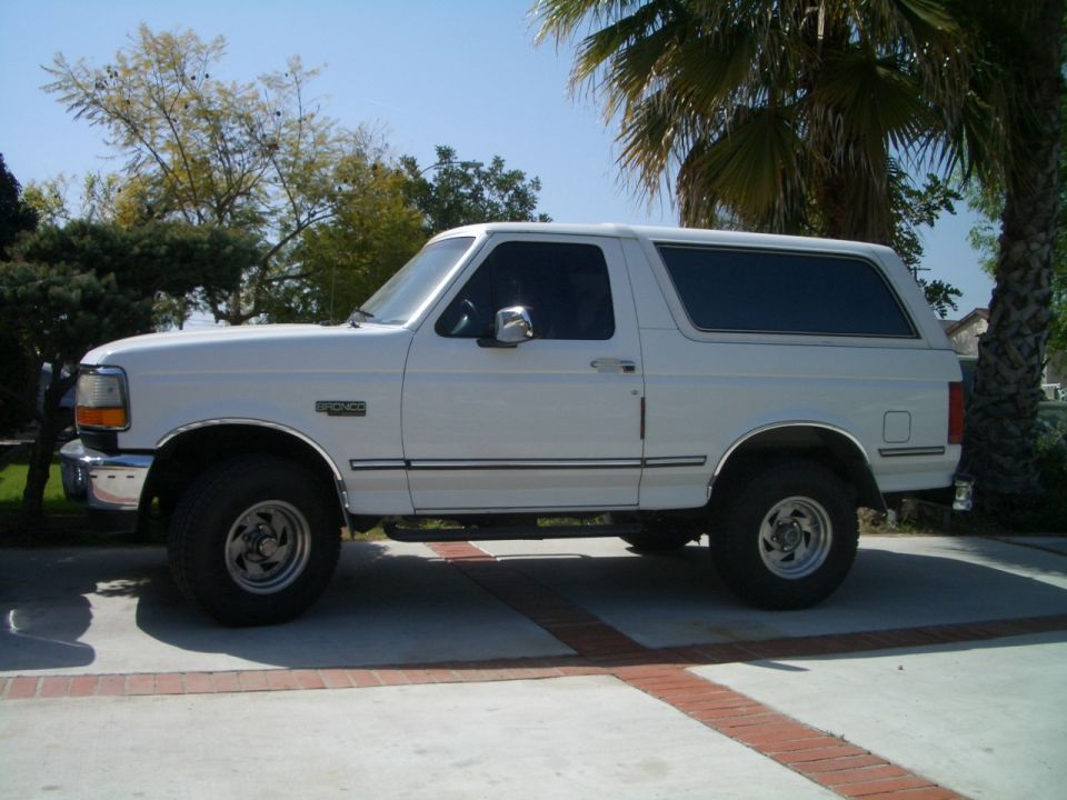White 1992 Ford Bronco SUV parked on a paved driveway, side view