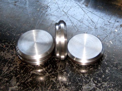 1996 Ford Bronco - Three circular metal parts, one viewed from the side, sit on a worn, textured surface.
