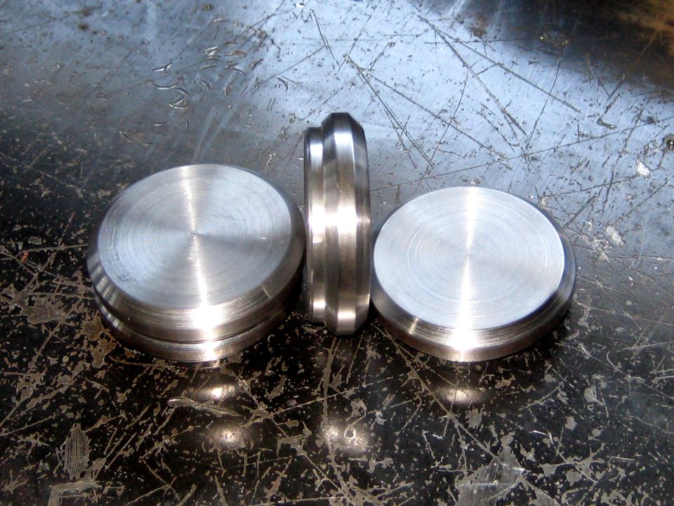 three machined metal parts on a scratched surface