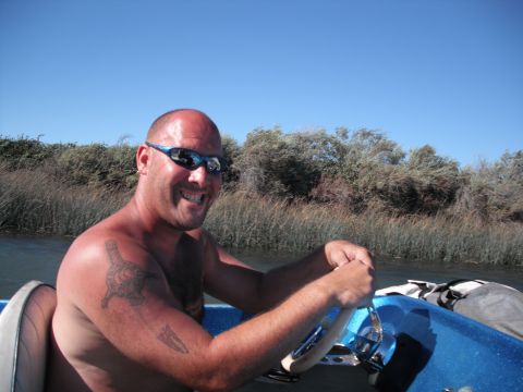 1991 Ford Bronco - Man at the helm of a boat on a sunny day, surrounded by vegetation.