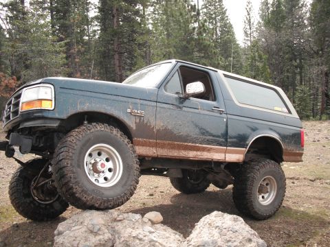 1991 Ford Bronco - Mud-covered 1991 Ford Bronco navigating rocks during an off-road excursion.