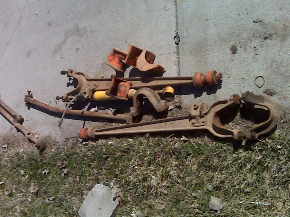 Rusty leaf springs and suspension arms laid out on grass