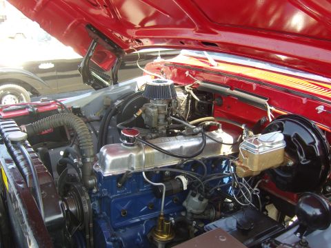 2007 Ford Mustang - Close-up view of a red engine bay a blue engine block and chrome valve cover, with another vehicle partially visible in the background.