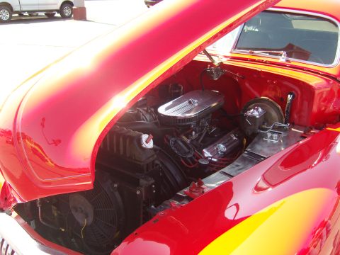 2007 Ford Mustang - Engine bay of a red classic car, a V8 engine with a chrome air cleaner and a large cooling fan.