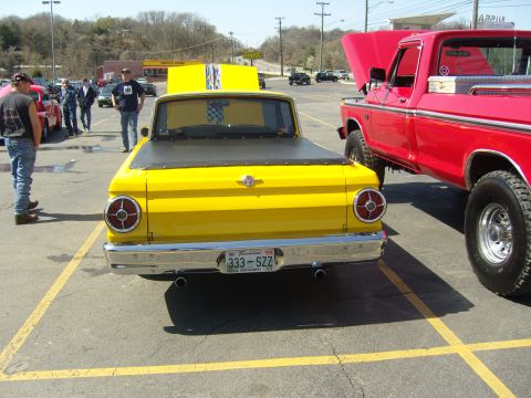 2007 Ford Mustang - A yellow pickup truck from the 1960s is parked next to a red pickup truck at a car meet.