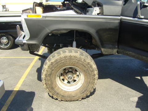 2007 Ford Mustang - Close-up view of a lifted pickup truck's front wheel and fender, with another vehicle visible in the background.