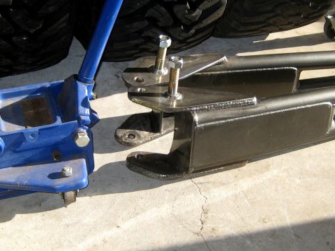 1996 Ford Bronco - A blue hydraulic jack sits beside black metal suspension components, ready for installation or repair.