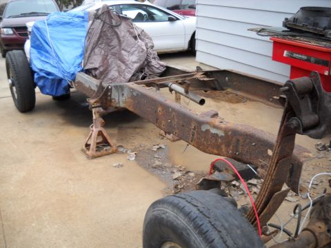 1954 Ford F-100 - Truck chassis undergoing restoration, with some components covered by tarps.