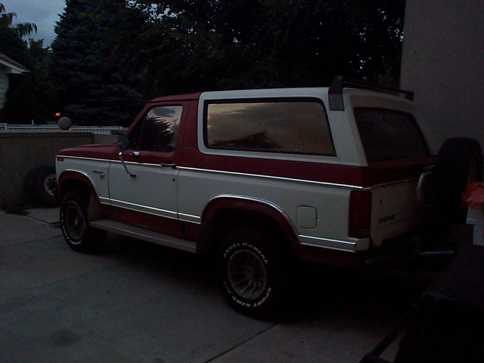 Two-tone red and white Ford Bronco with a spare tire mounted on the rear