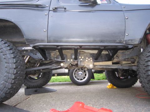 1996 Ford Bronco - The undercarriage of a modified SUV shows heavy-duty suspension and protective rock sliders.